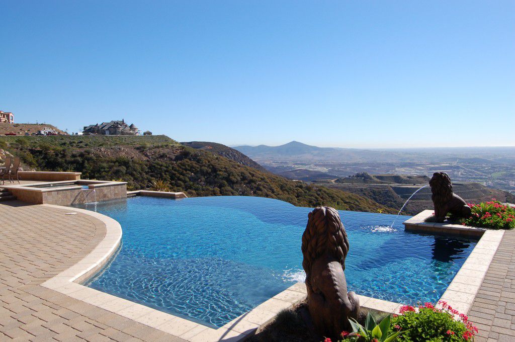 A beautiful pool with an infinity edge looking over the San Diego landscape with two lion fountains.