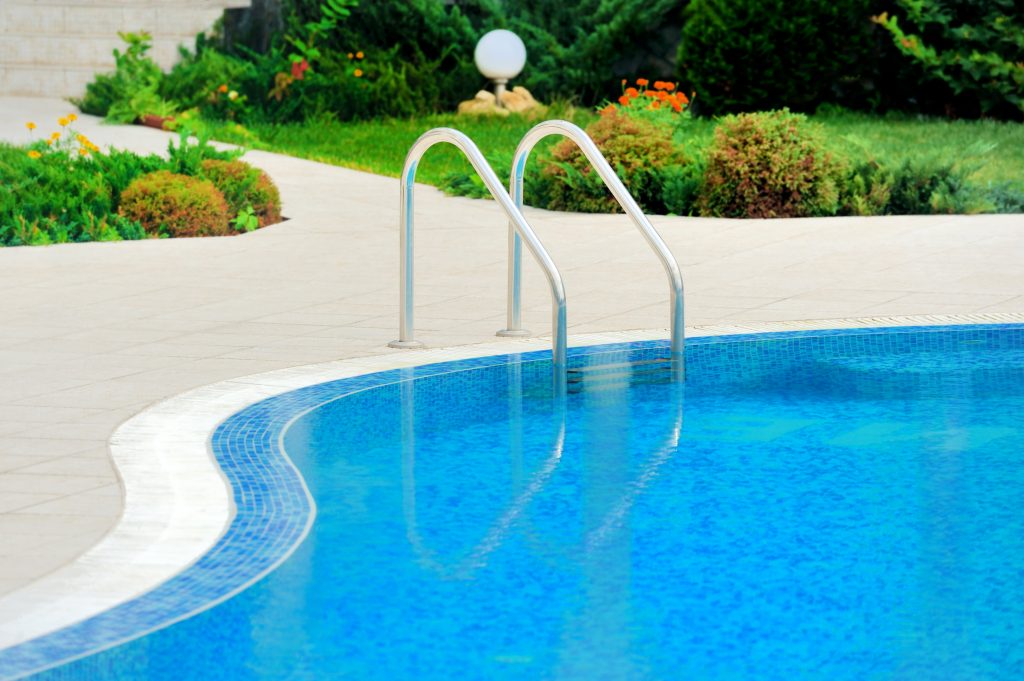 A closeup of a freeform swimming pool with a pool ladder.