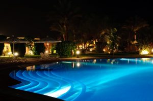 A photo taken at night of a swimming pool illuminated by blue LED lights.