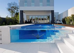 A luxury swimming pool with a transparent side where you can see a man swimming.