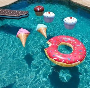 A variety of food shaped swimming pool floats that are floating in water.