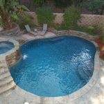 Freeform pool with raised spa featuring rock steps in a residential backyard in San Diego.