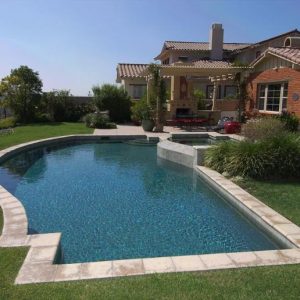 Freeform pool and spa with green lawn.