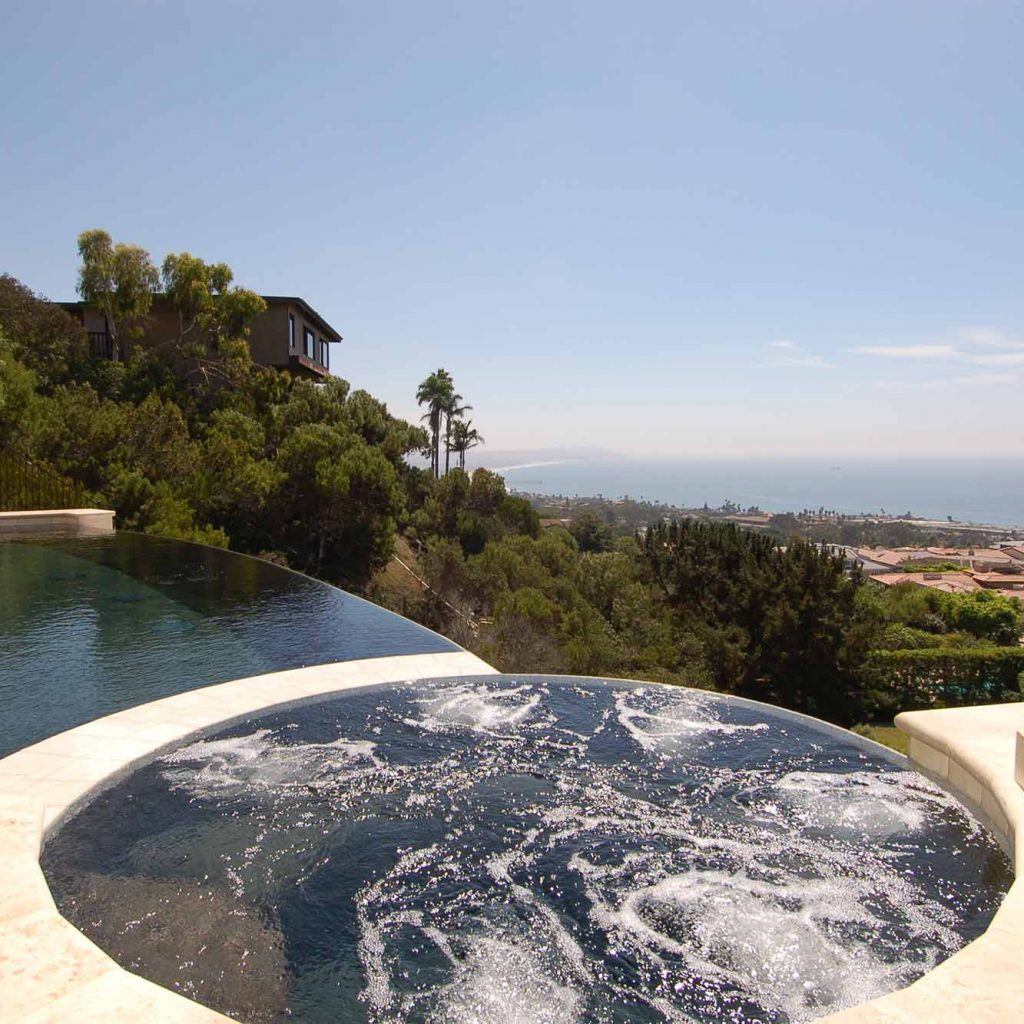 Close up of bubbling custom spas with an infinity edge pool.