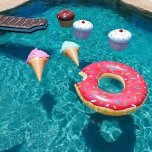 A variety of food shaped swimming pool floats that are floating in water.