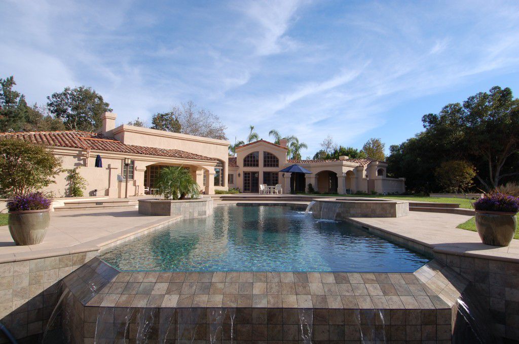 A beautiful infinity edge pool and house in background.