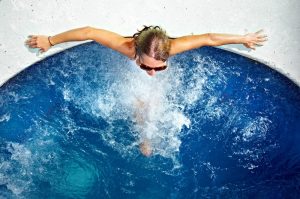 Woman relaxing in bubbly spa wearing sunglasses.